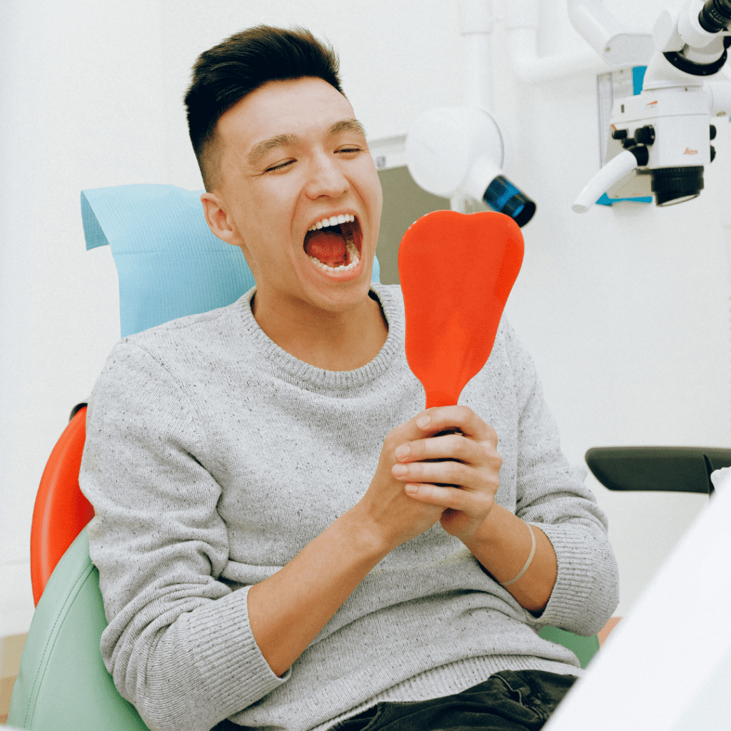 hollywood smile where a patient is checking the result of treatment with help of a mirror