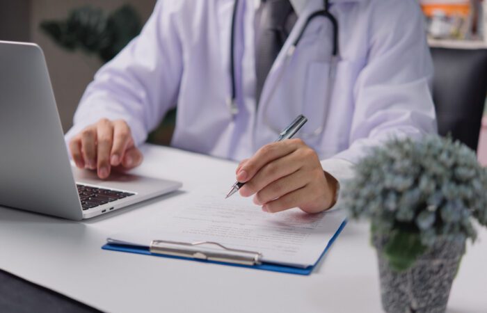 form being filled by doctor while working on laptop