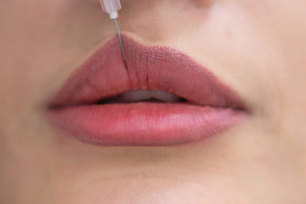 A thoughtful Grecian esthetician gazes into a mirror, her curly hair framing her face. Holding a beauty injection syringe, she contemplates the ideal treatment.